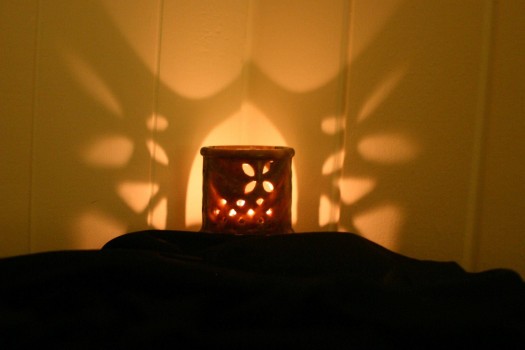 candle casting patterns of light on the wall