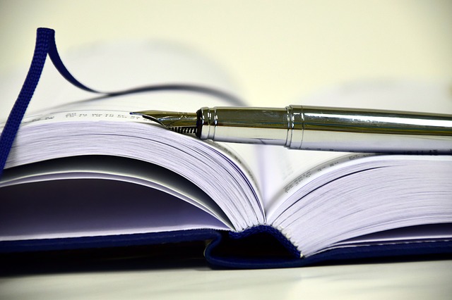 an image of an open book with a fountain pen balanced on top