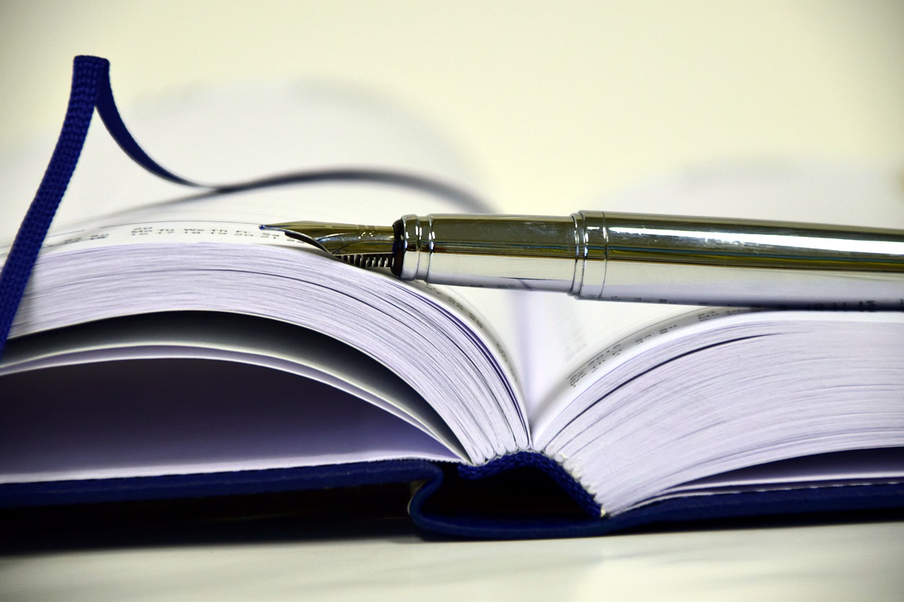 Breakout Novel Dissection group image of an open notebook with a pen laying over the top.