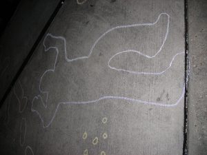 chalk outline of a body, with outlines of bullet casings nearby
