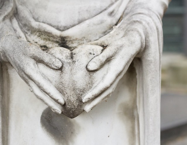 Closeup of a statue holding a heart in its hands.