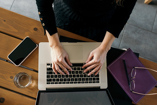 Overhead view of a person's hands typing on a laptop