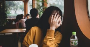 Woman hiding her face with a hand.