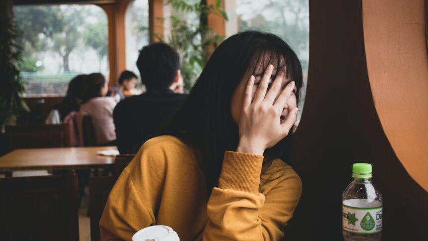 Woman hiding her face with a hand.