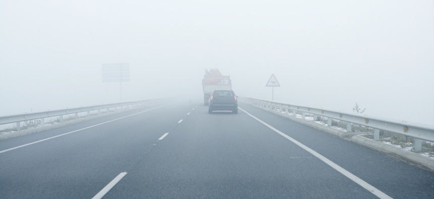 Foggy gray road, cars driving vanish into the fog