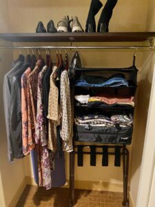 image of women's clothes hanging in a closet next to a set of hanging shelves.