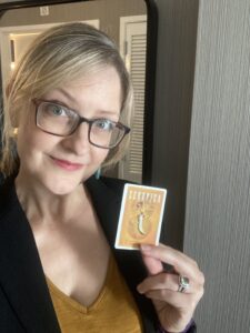Author Greer Macallister holding a playing card showing the cover of her book Scorpica.