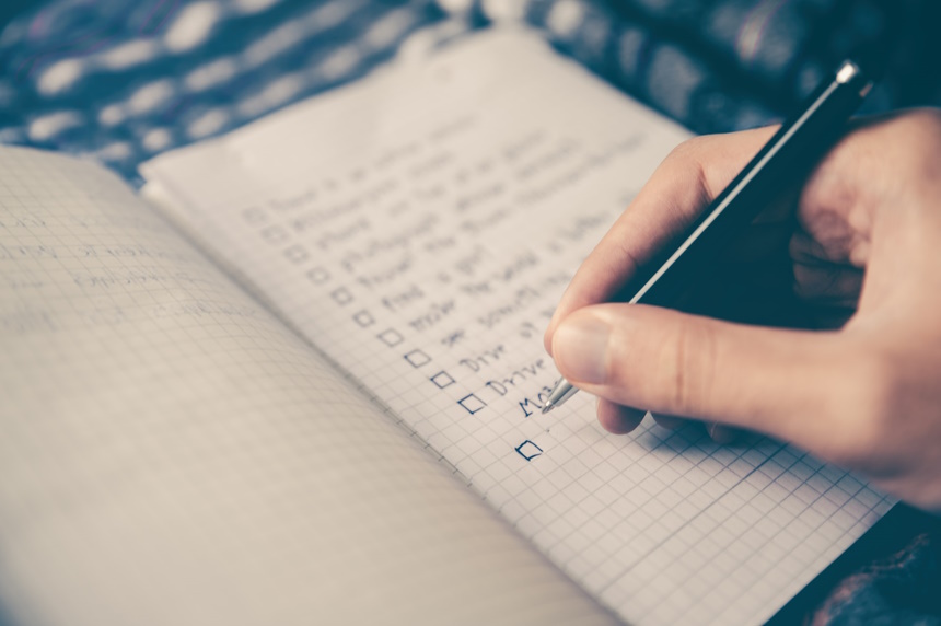 Photo by Glenn Carstens-Peters via Unsplash hand holding pen over checklist
