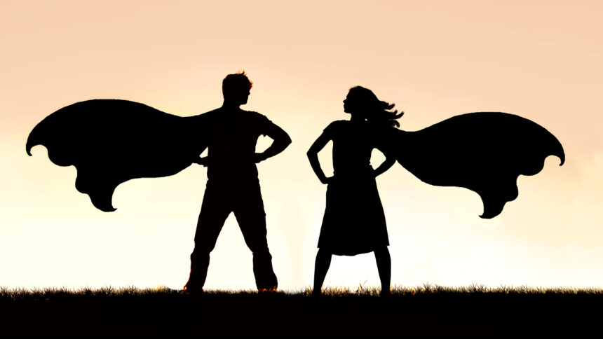 A silhouette of a superhero man and woman couple in capes standing strong and powerful against a sunset sky background.