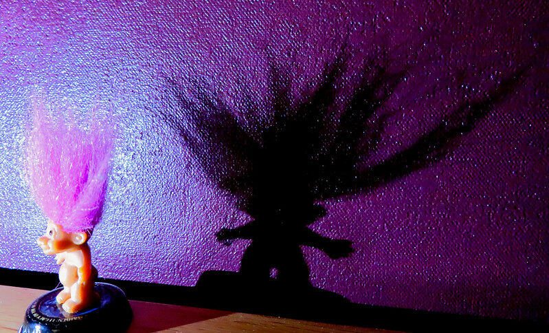 Header image: Troll with purple hair casting dark shadow on a purple backround