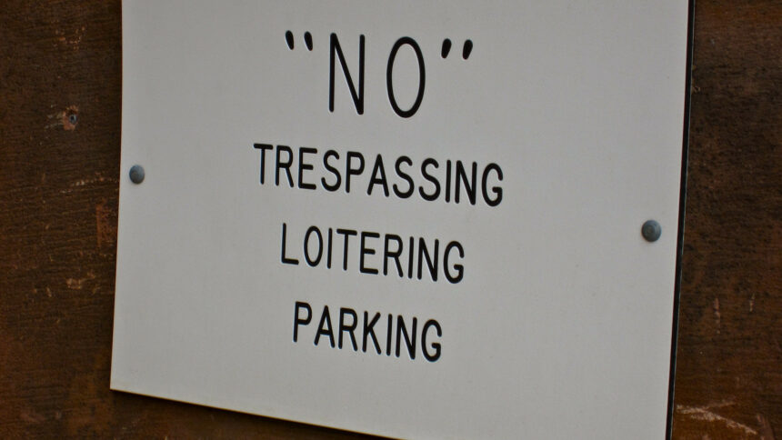 A black and white sign that says "NO" trespassing, loitering, parking. For some reason, there are quotations around the word, "NO."