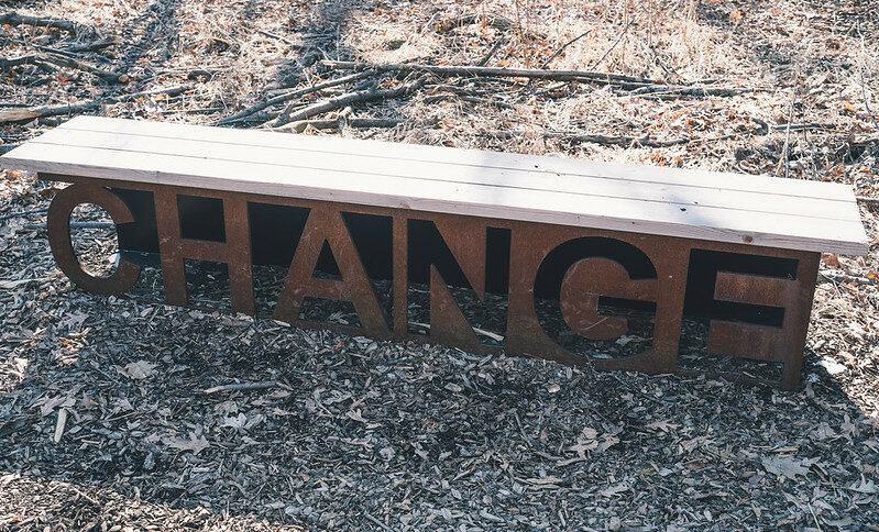 Header image: Wooden bench resting on metal sculpture saying "Change" on a ground of woodchips and fallen leaves. (Credit: Conal Gallagher / https://www.flickr.com/photos/conalg/17250403565/ )