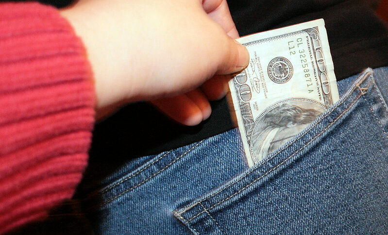 Header image: a hand slipping a $100 bill out of someone else's back pocket