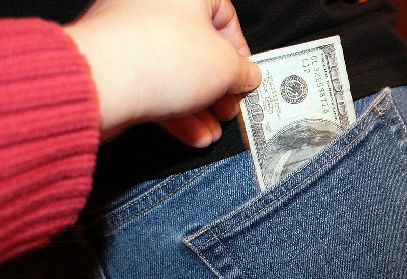 Header image: a hand slipping a $100 bill out of someone else's back pocket