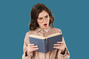white woman with brown hair and glasses, holding an open book with an offended expression on her face, on a teal background