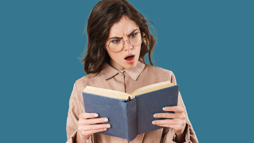 white woman with brown hair and glasses, holding an open book with an offended expression on her face, on a teal background