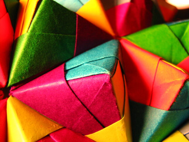 A brightly-colored, multifaceted origami series of pyramids that form a large ball.
